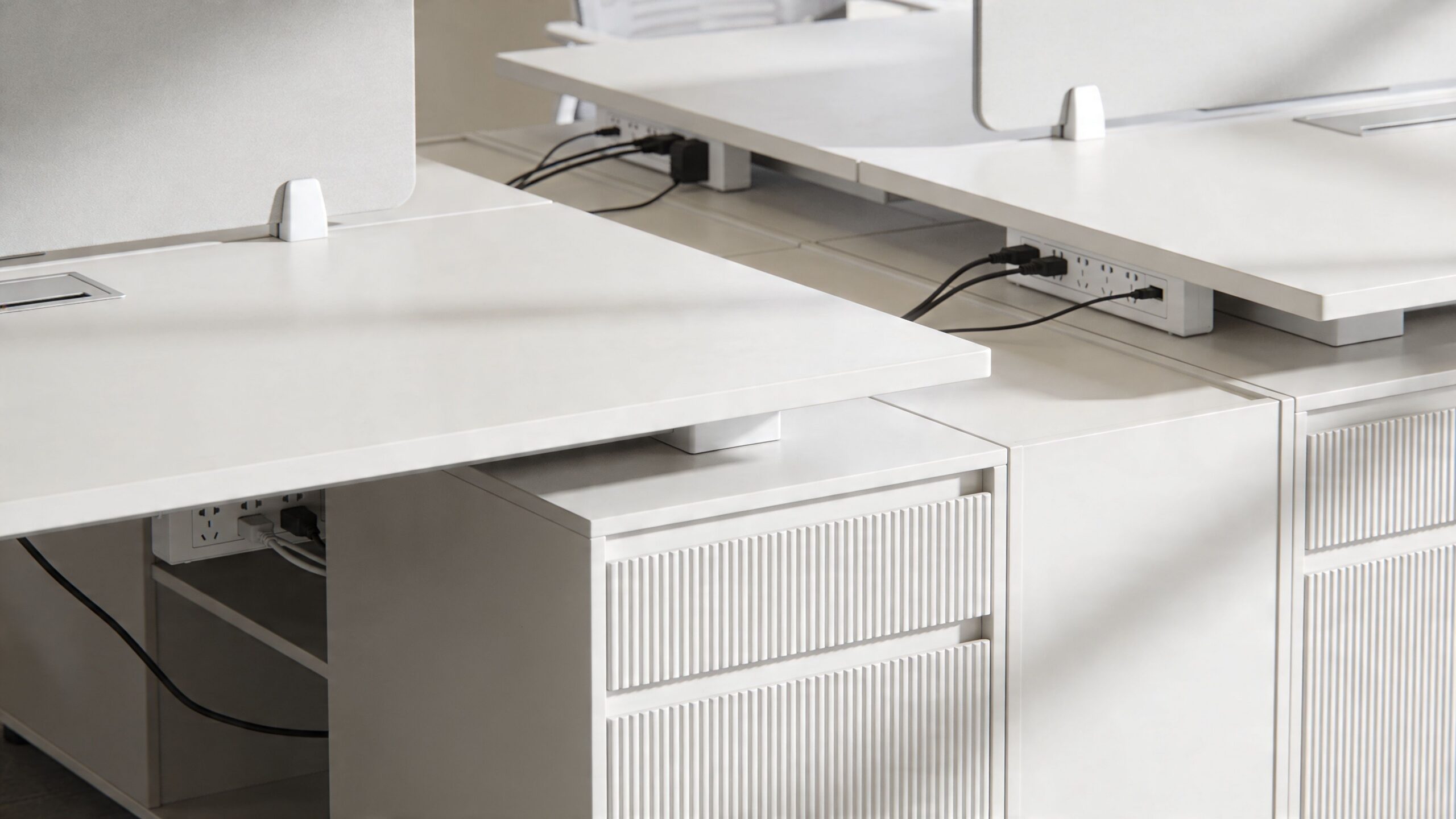 A minimalist white office desk with integrated power strips and modern textured drawer storage units.